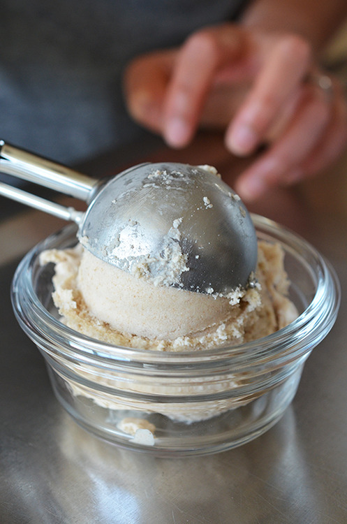 Placing a scoop of paleo and Dairy-Free Vanilla Ice Cream in a clear dish.