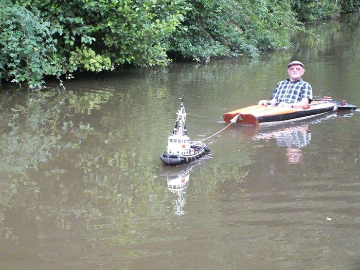 rc tugboat tows man in kayak down english canal...