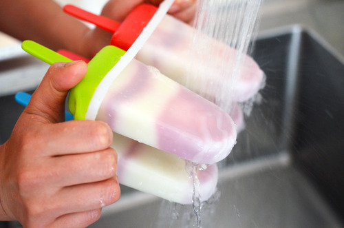 Running hot water over the ice pop molds to loosen them up.