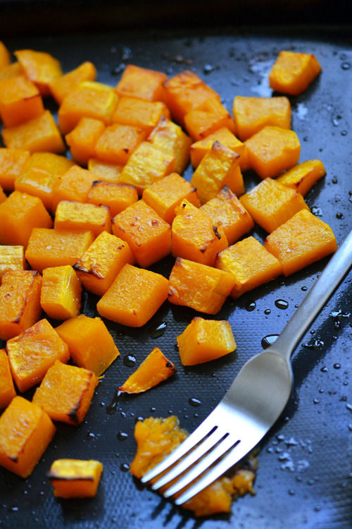 Baked and cubed butternut squash on a sheet pan.