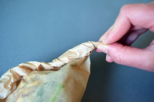 The ends of the parchment packets are tightly twisted to seal everything shut.