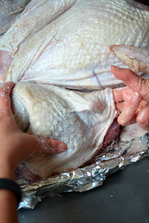 Someone using their fingers to separate the turkey skin from the meat.