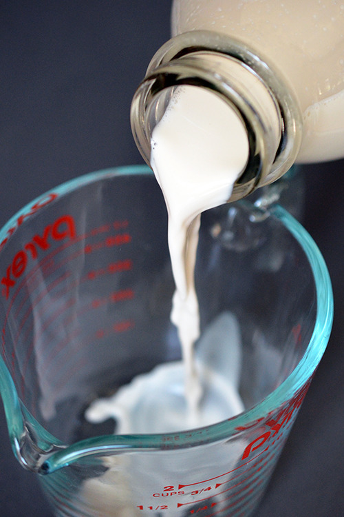 Pouring almond milk into a measuring cup.
