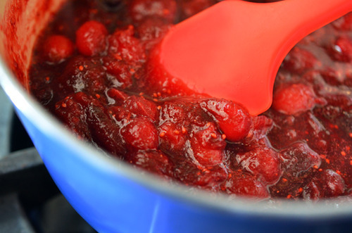 Mixing the ingredients for paleo cran-cherry sauce in a pot with a rubber spatula.