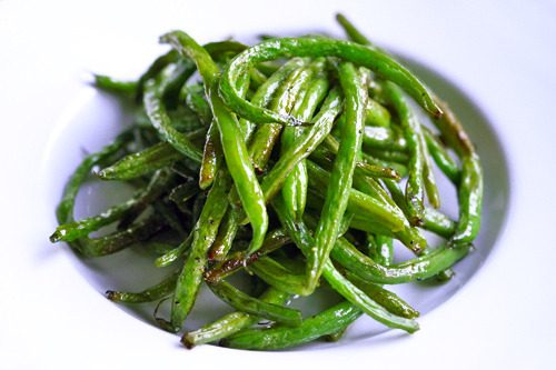 A closeup of a plate of roasted green beans.