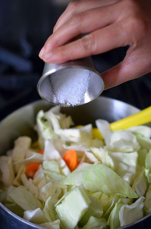 Adding some salt to a saucepan filled with vegetables for atakilt.