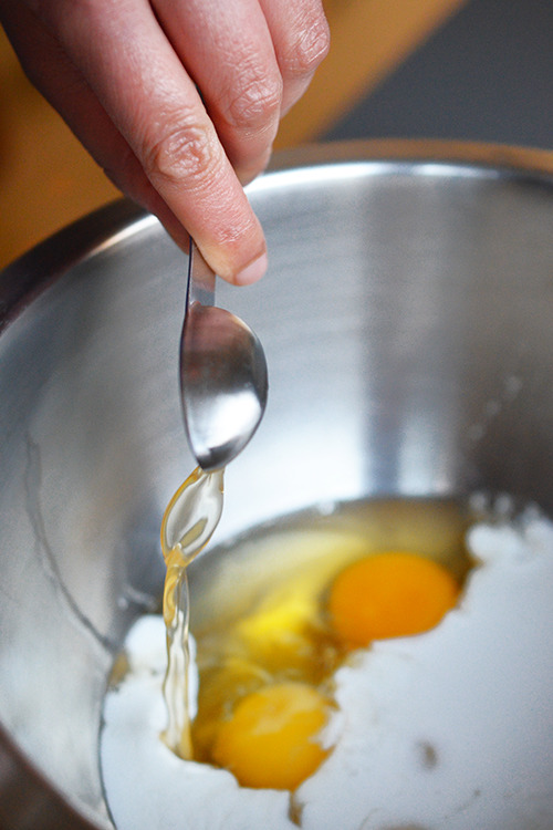 A teaspoon of vinegar is poured into the paleo pancake batter.