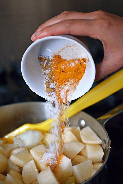 Pouring the spices into a pot of paleo Atkilt Ethiopian Vegetable Stew.