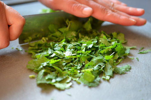 Side shot of someone mincing fresh cilantro for Warm Brussels Sprouts Slaw with Asian Citrus Dressing 