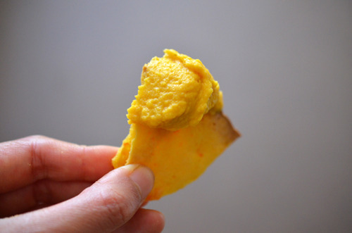 Someone holding a piece of grain-free pita bread with butternut squash dip.