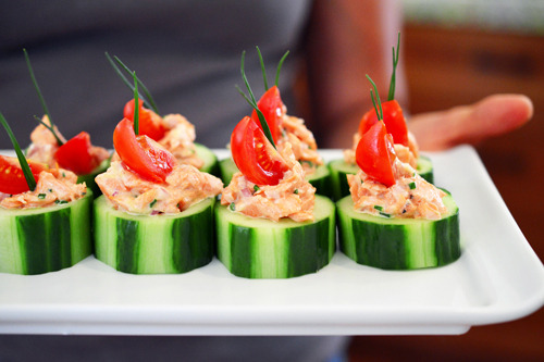 Someone holding a white plate with paleo spicy salmon cucumber bites.