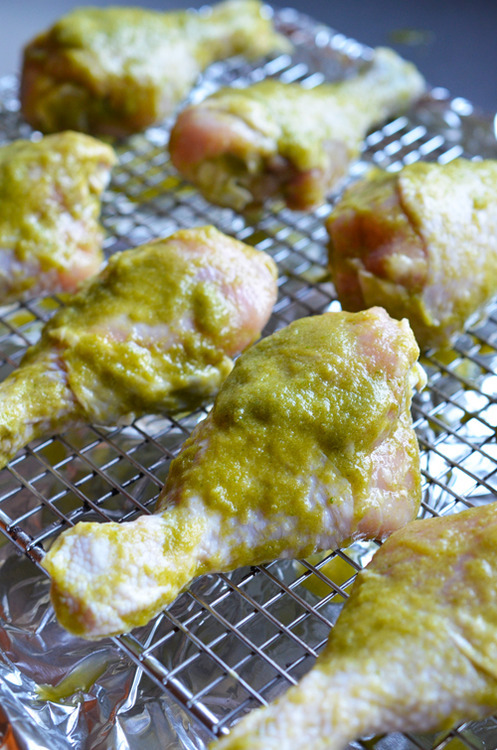 Raw chicken drumsticks after being marinated lined on a wire rack prepped to be cooked.
