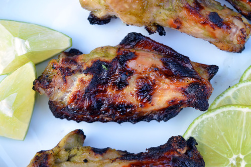 Chili lime chicken wings on a plate with cut up limes.