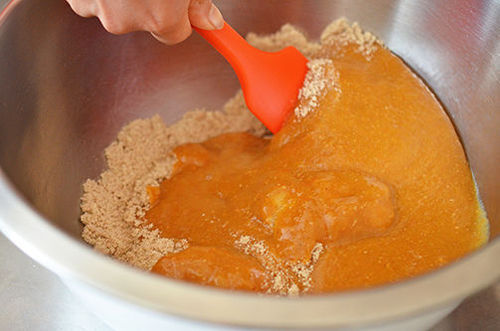 Stirring the batter for healthy Paleo Pumpkin and Carrot Muffins with a red silicone spatula.