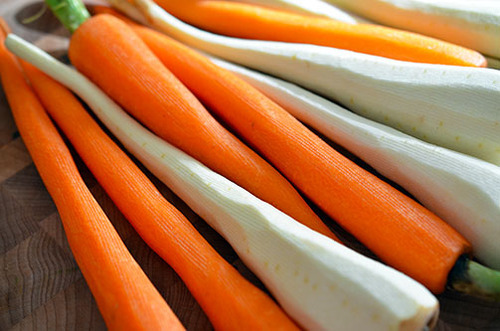 A row of washed and peeled carrots in different colors.
