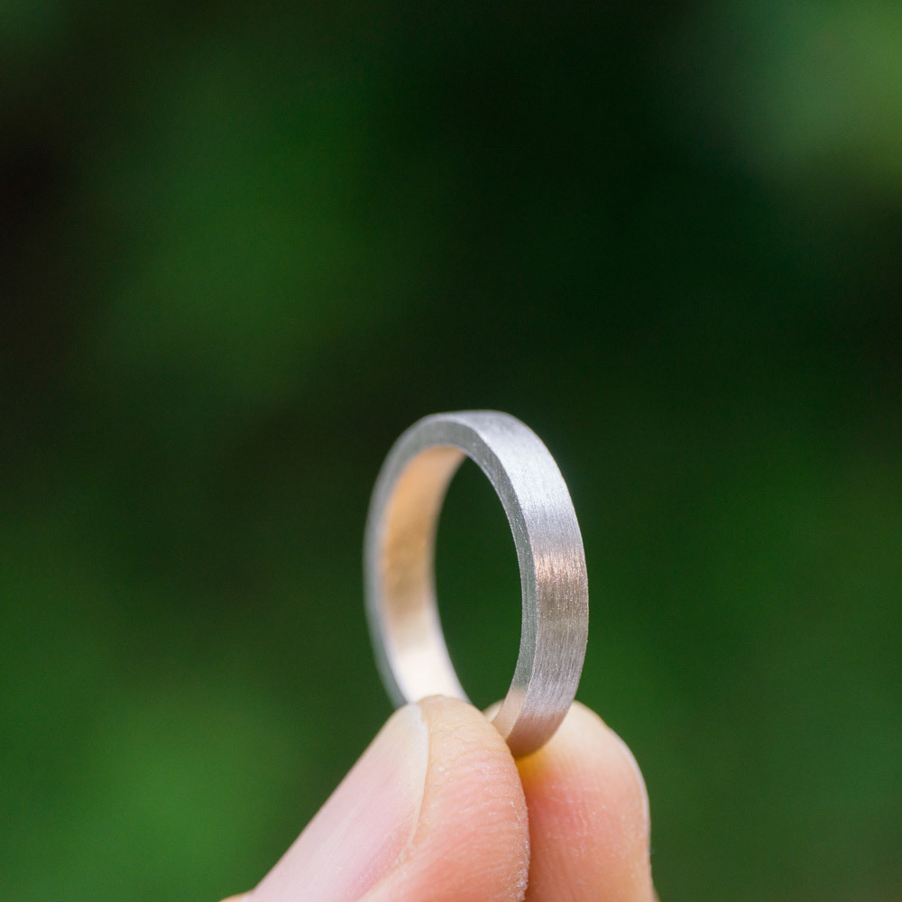 結婚指輪の制作風景　ゴールド、プラチナリング　屋久島の緑バック手に持って　屋久島で作る結婚指輪