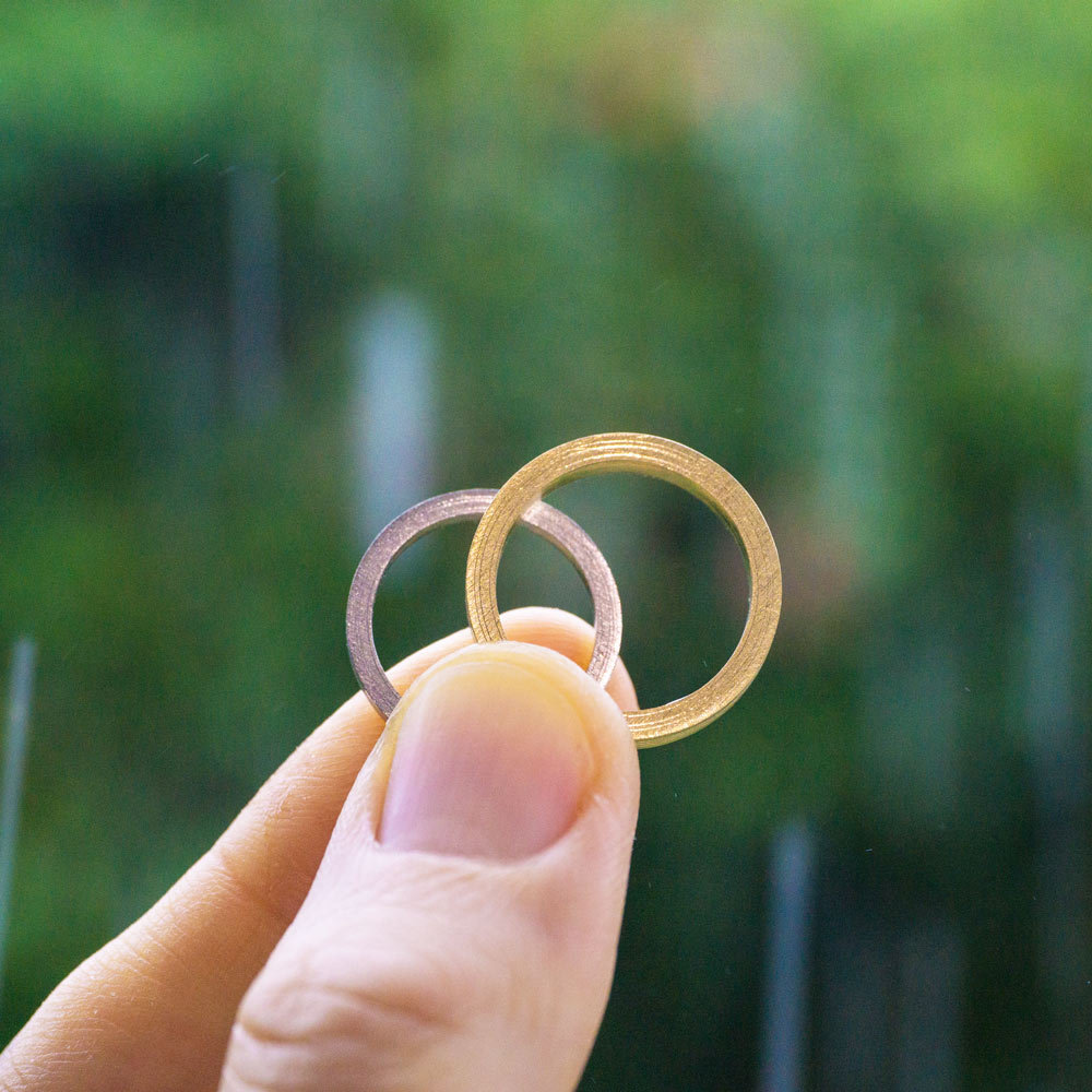 屋久島で作る結婚指輪　屋久島の緑バック　手にとって　プラチナとゴールドのリング　