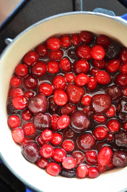 A pot of cherries and cranberries on the stove.