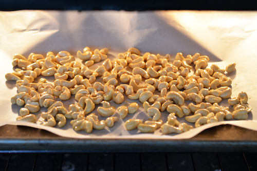 Honey vanilla cashews on a tray in the oven ready to be baked.