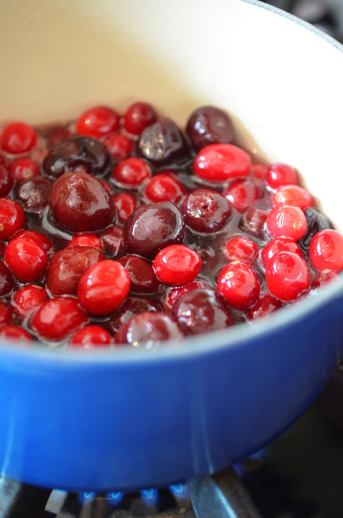 A pot of cranberries and cherries coming to boil.