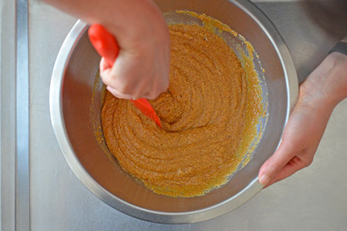 An overhead shot of someone mixing the batter for Paleo Pumpkin and Carrot Muffins until everything is uniform.