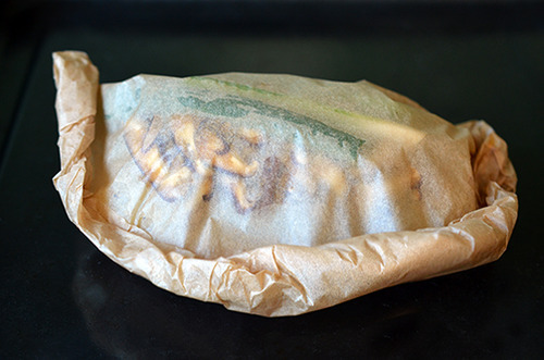 A Fish en Papillote with Citrus, Ginger, & Shiitake is placed on a rimmed baking sheet.