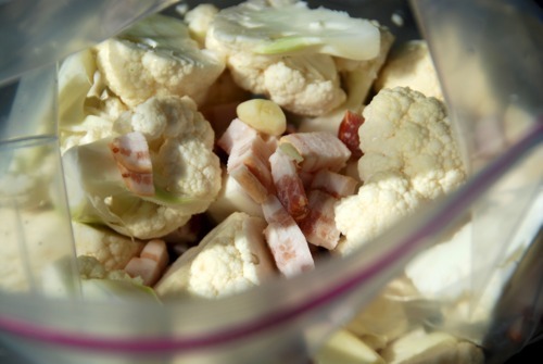 Garlic, cauliflower, and bacon in a Ziploc bag being prepped to be sous vide.