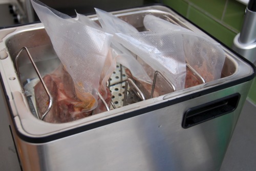 Four packets of seasoned pork chops in a SousVide Supreme.