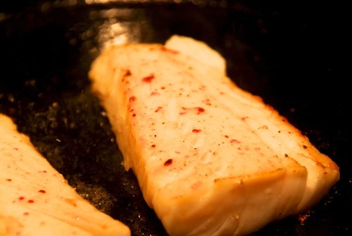 Alaskan cod fillets cooked sous vide searing off on a cast iron skillet.
