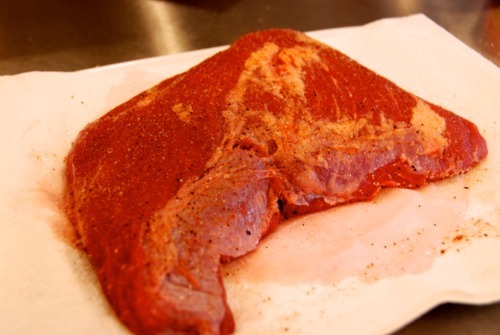A dried and seasoned grass fed tri-tip roast sitting on a paper towel.