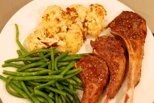 A dinner plate consisting of paleo and Whole30 sous vide lamb chops, roasted cauliflower, and microwaved green beans.