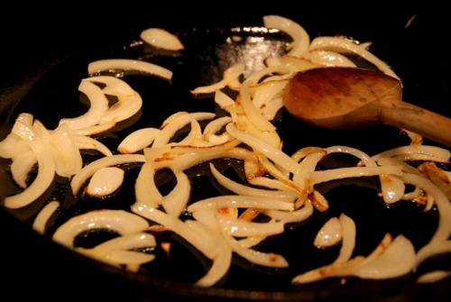 Sliced onions sautéing in a cast iron skillet.