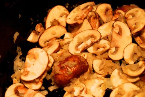 Sautéd cremini mushrooms in a cast iron pan with onions.