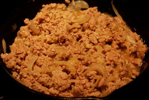 Ground pork and onions cooked in a cast iron skillet.