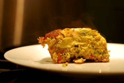 A slice of curried ground pork and broccoli slaw frittata sitting on a plate.