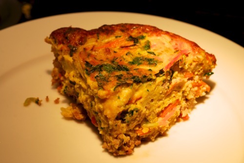 A slice of curried ground pork and broccoli slaw frittata sitting on a plate.