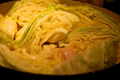 A Dutch oven filled with large slices of cabbage.