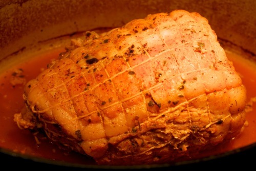 A pork leg being roasted in a Dutch oven.