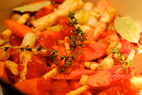 Thyme sprigs on top of a carrots, parsnip, and tomato medley.