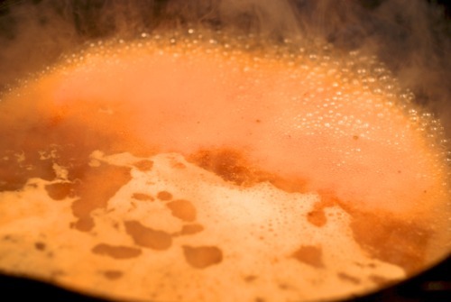 Chicken broth boiling in a cast iron skillet.