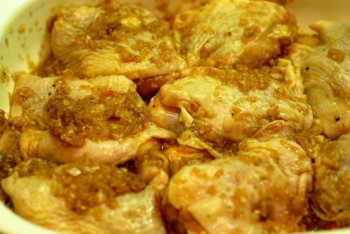 Chicken thighs are laid in a baking dish with sauce poured on top.
