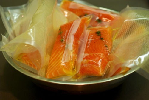 A metal bowl filled with vacuum sealed salmon fillets.