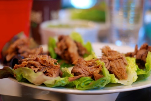 Shredded pork on top of butter lettuce leaves served on a plate.