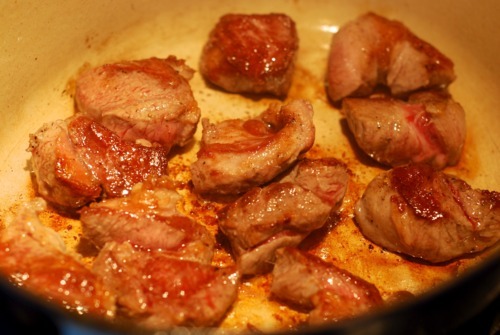 Lamb pieces searing in a Dutch oven with ghee.