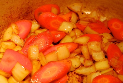Carrots and onions being fried in a Dutch oven for Rogan Josh lamb stew.