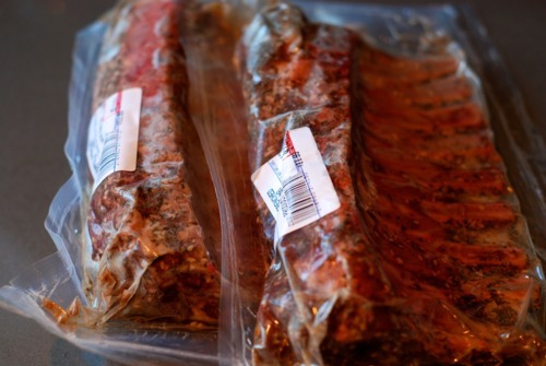 Seasoned and frenched rack of lamb sealed in plastic packaging.
