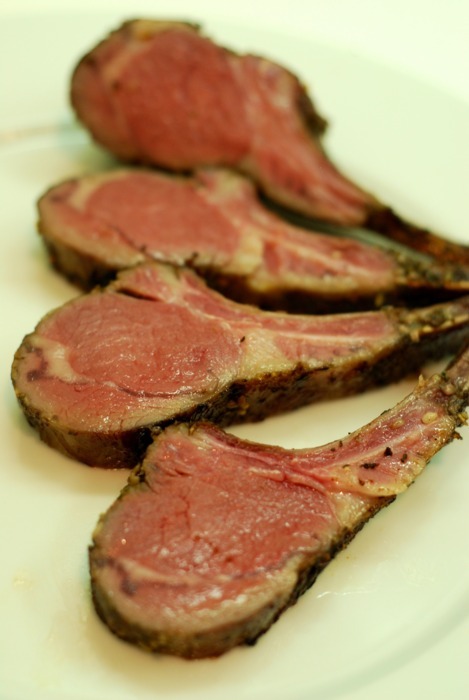Four lamb chops sitting on a plate after having been cooked sous vide and seared.