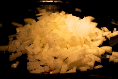 A pile of diced onions on a cast iron skillet ready to be sautéed.