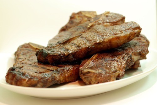 A plate of stacked grass fed t-bone steaks that are cooked sous vide and seared on the grill.
