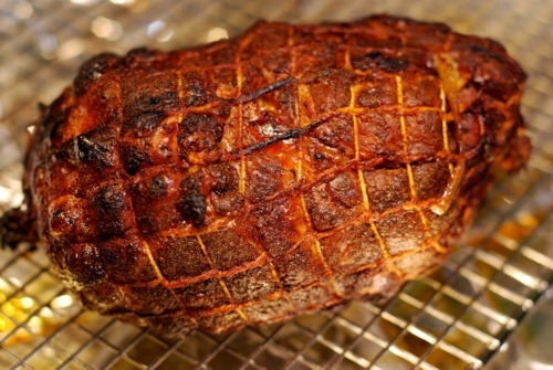 A broiled pork shoulder is sitting on a wire cooling rack.